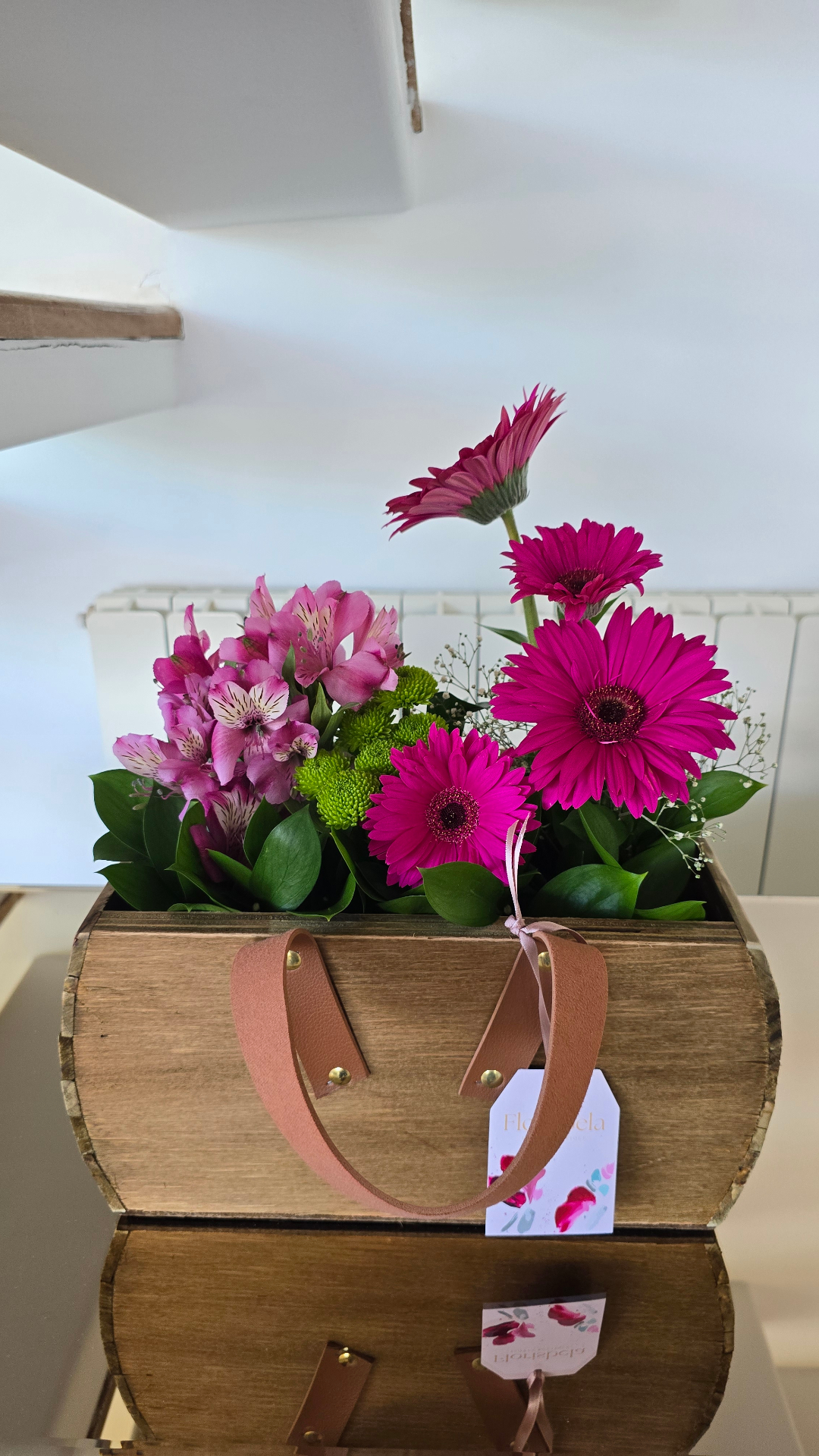Arranjo de mesa em caixote de madeira com gérberas magenta e alstromérias rosa.